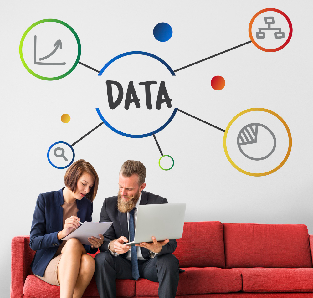 Professional man and woman sitting on a red couch analyzing customer data on a laptop, surrounded by a vibrant infographic showing data flowing into a central 'DATA' hub with icons for insights, growth, and analytics.